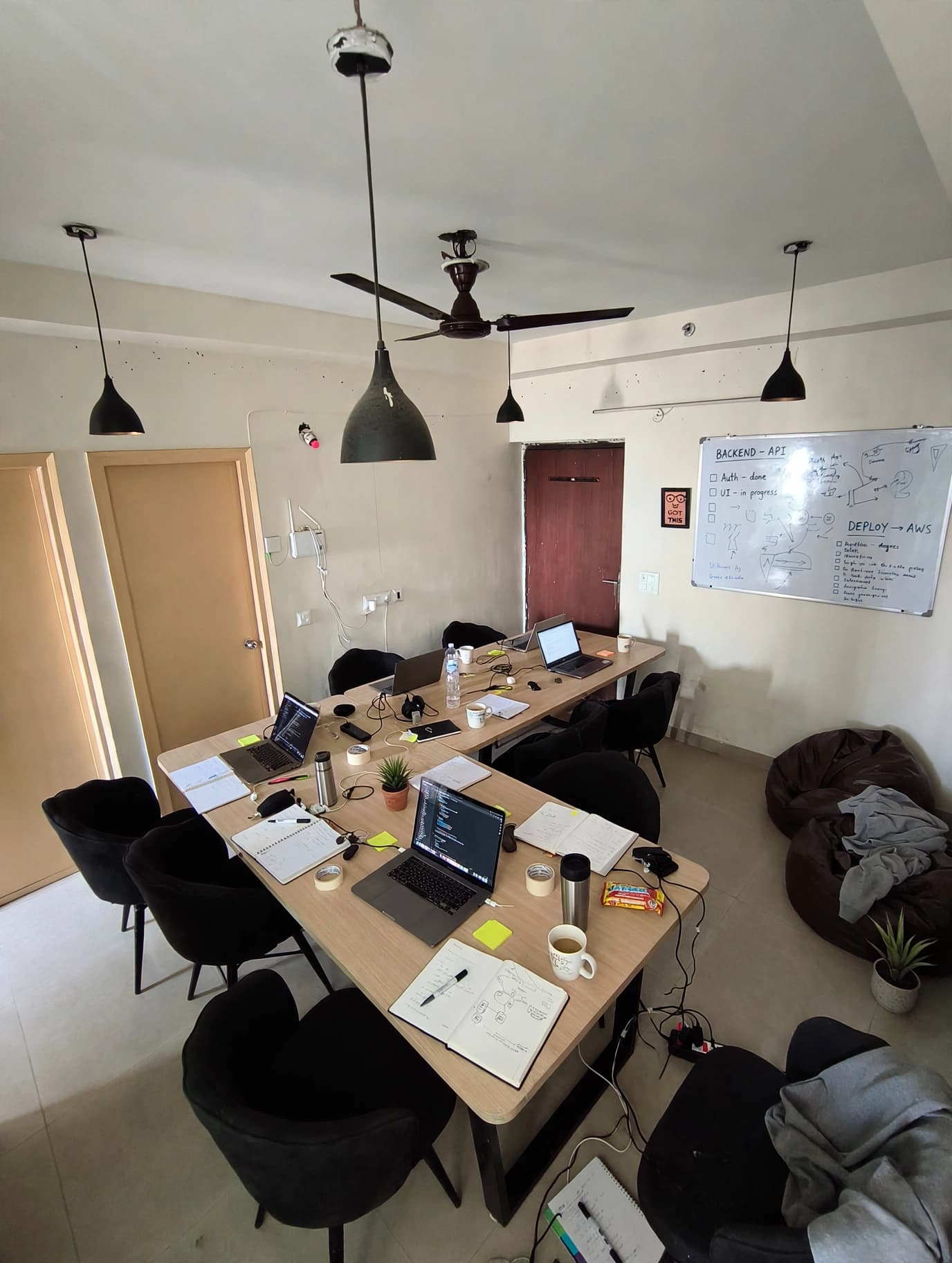 The shared worktable inside Flat 605, prepared with laptops, notebooks, chairs, and a planning whiteboard